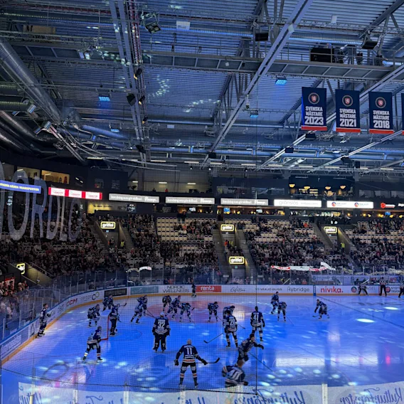 Ishockeyspelare pa en blalyst rink under en match i en arena med Svenska Mastare-vepor.