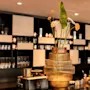 Et hyggeligt bar- eller loungeområde med et blomsterarrangement og oplyste hylder, der viser glasvarer.