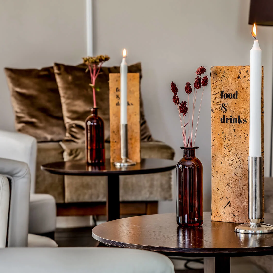Candles on a table with a menu in a cozy living room setup.
