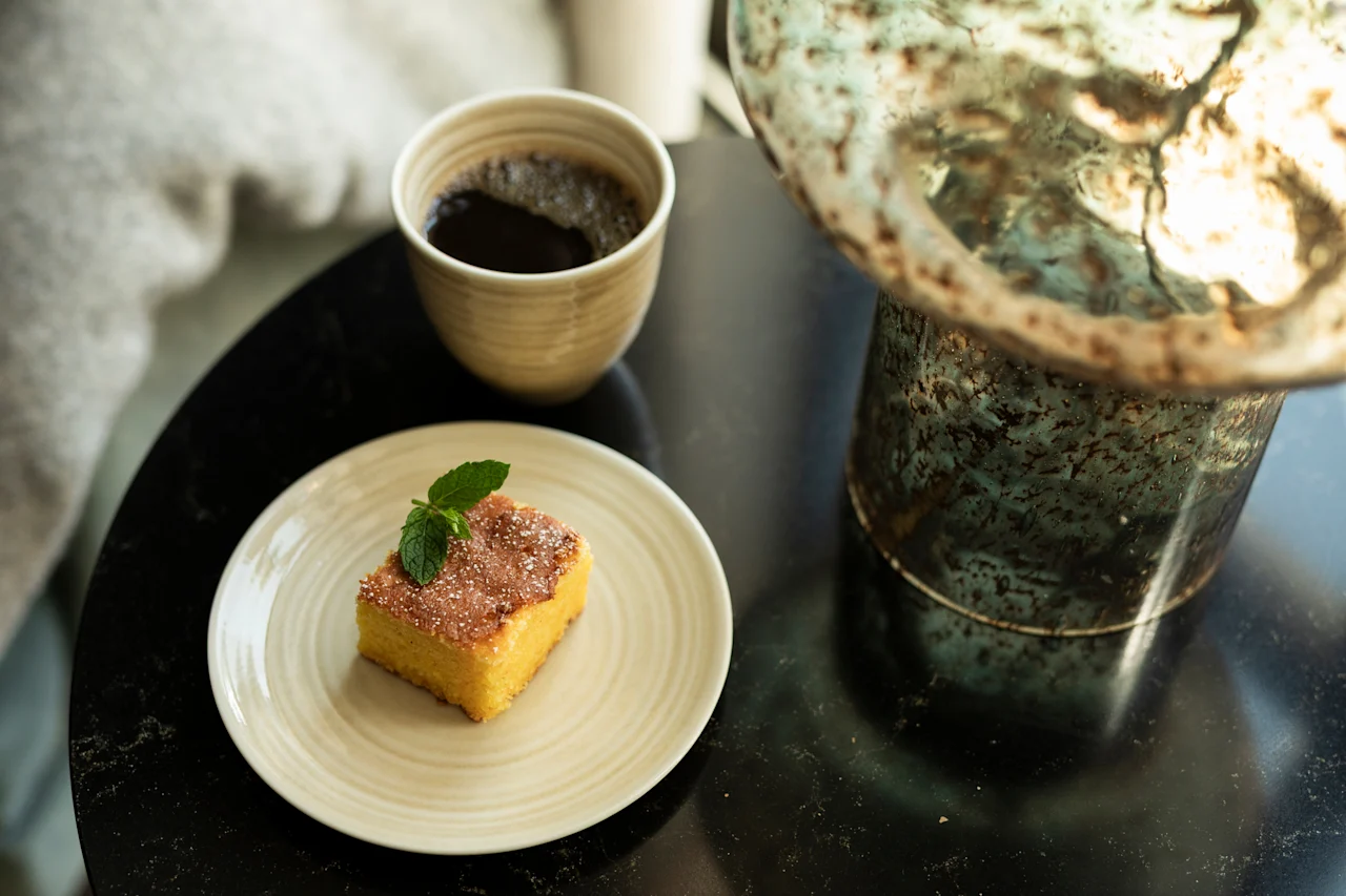 Et lækkert stykke kage med myntepynt og en kop kaffe på et mørkt bord, der antyder en behagelig pause.