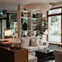 A warm and inviting hotel lobby with comfortable seating, a bookshelf, and a large window overlooking a street. EXIT sign visible.