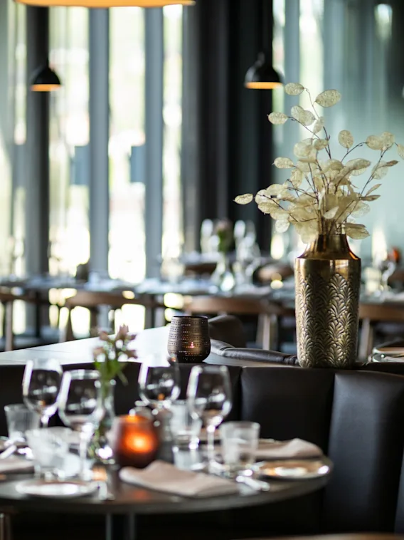 En stilfull restauranginredning med dukade bord, bekväma sittplatser och varm belysning, vilket skapar en inbjudande atmosfär.