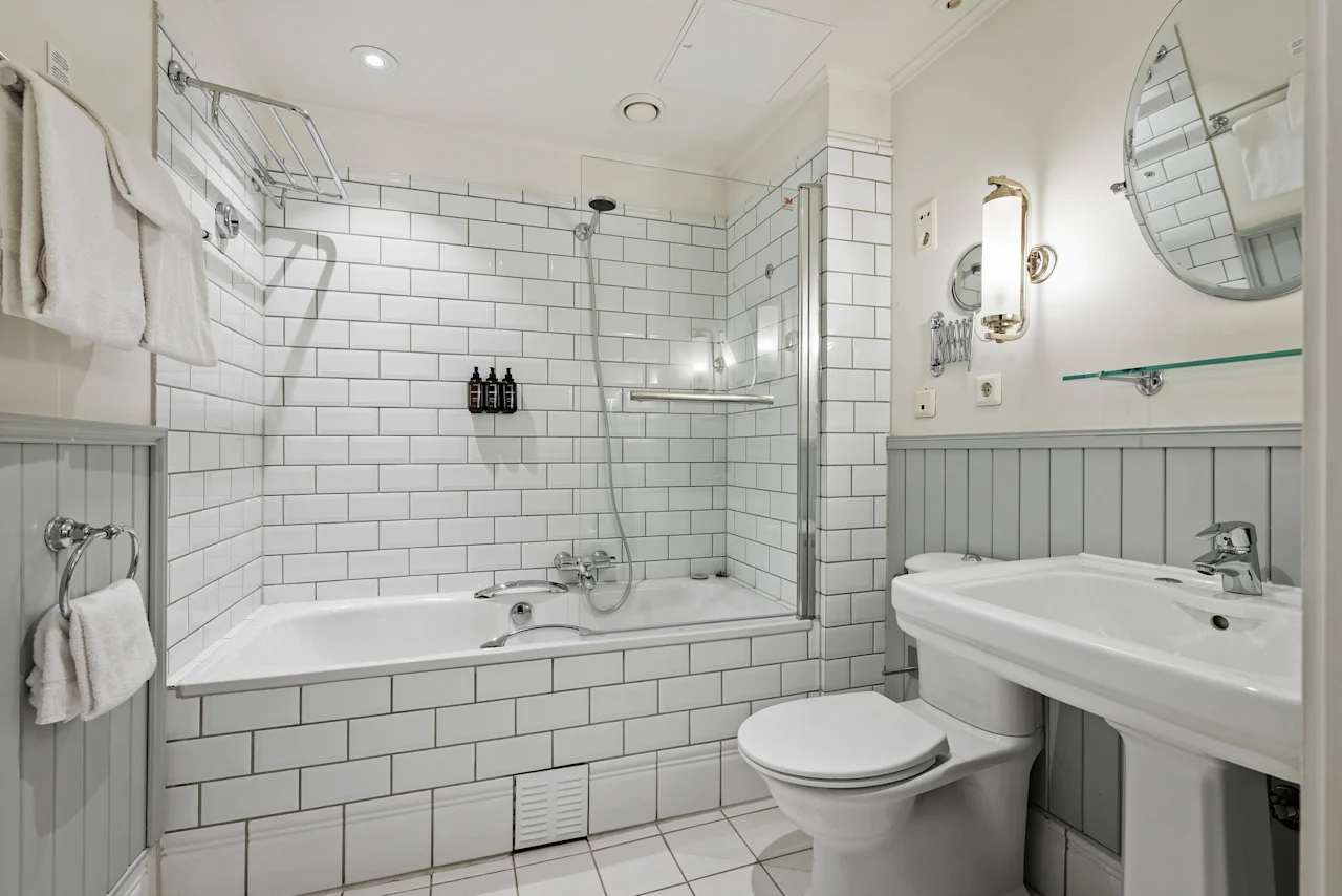A bright and clean bathroom featuring a bathtub with a shower, a toilet, and a sink, all in a modern design.