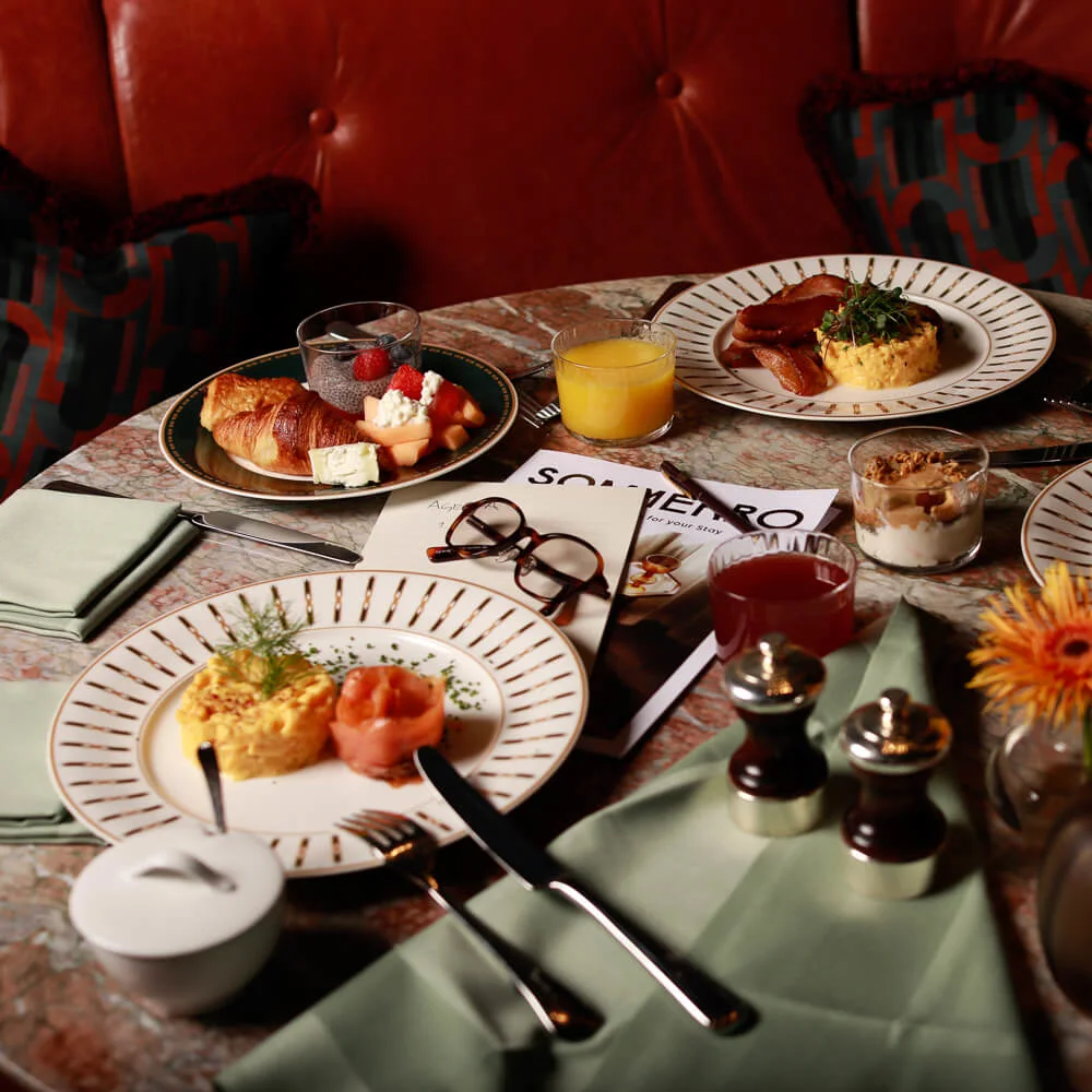 Forskellige morgenmadsretter på et bord, der antyder et delt måltid, i en hyggelig restaurantindstilling.