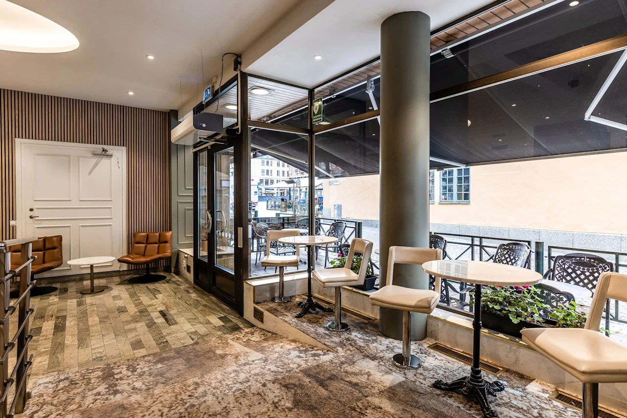 Viihtyisä sisätilojen oleskelualue, joka johtaa ulkoterassille kahvilapöytineen Comfort Hotel Linköping Cityssä.