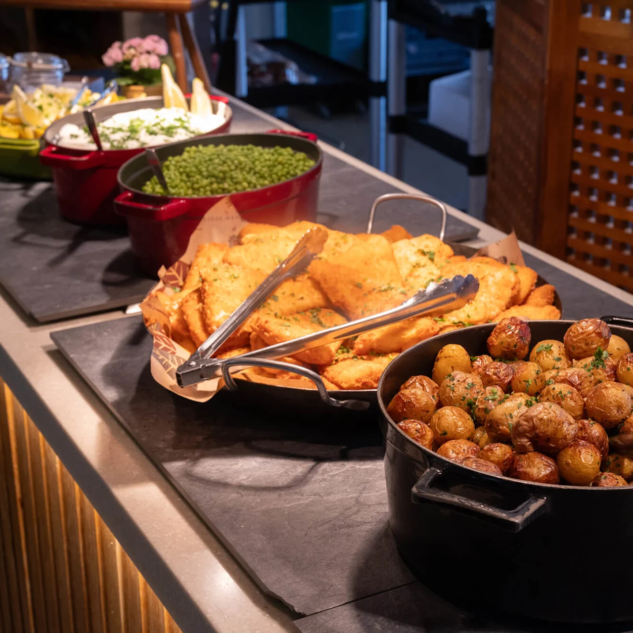 Various dishes are displayed on a buffet table ready for serving, including roasted potatoes, within an indoor dining setting.