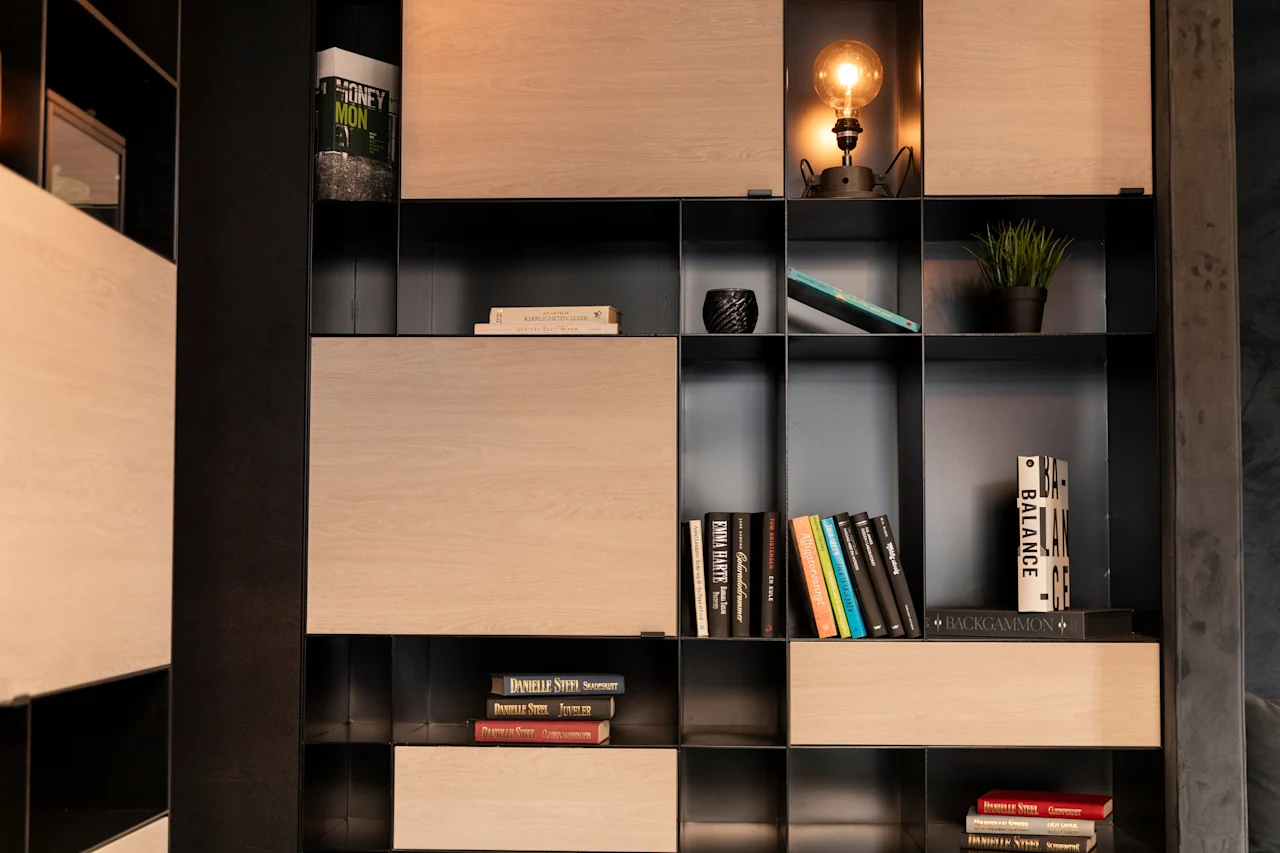 En moderne reol fyldt med bøger, en glødende lampe og et strejf af grønt, der antyder en behagelig læsekrog.