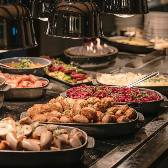 En deilig varm buffet med ulike varme retter, inkludert kjøttboller og pølser, klar for gjestene.