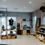 En butik viser forskellige ting som tøjdyr, kurve og tøj i en træindrettet, godt belyst indretning med snedækket udendørs udsigt gennem vinduerne.