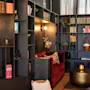 En koselig bibliotekslounge med mørke trebokhyller, en rød sofa og varm belysning, perfekt for avslapning.