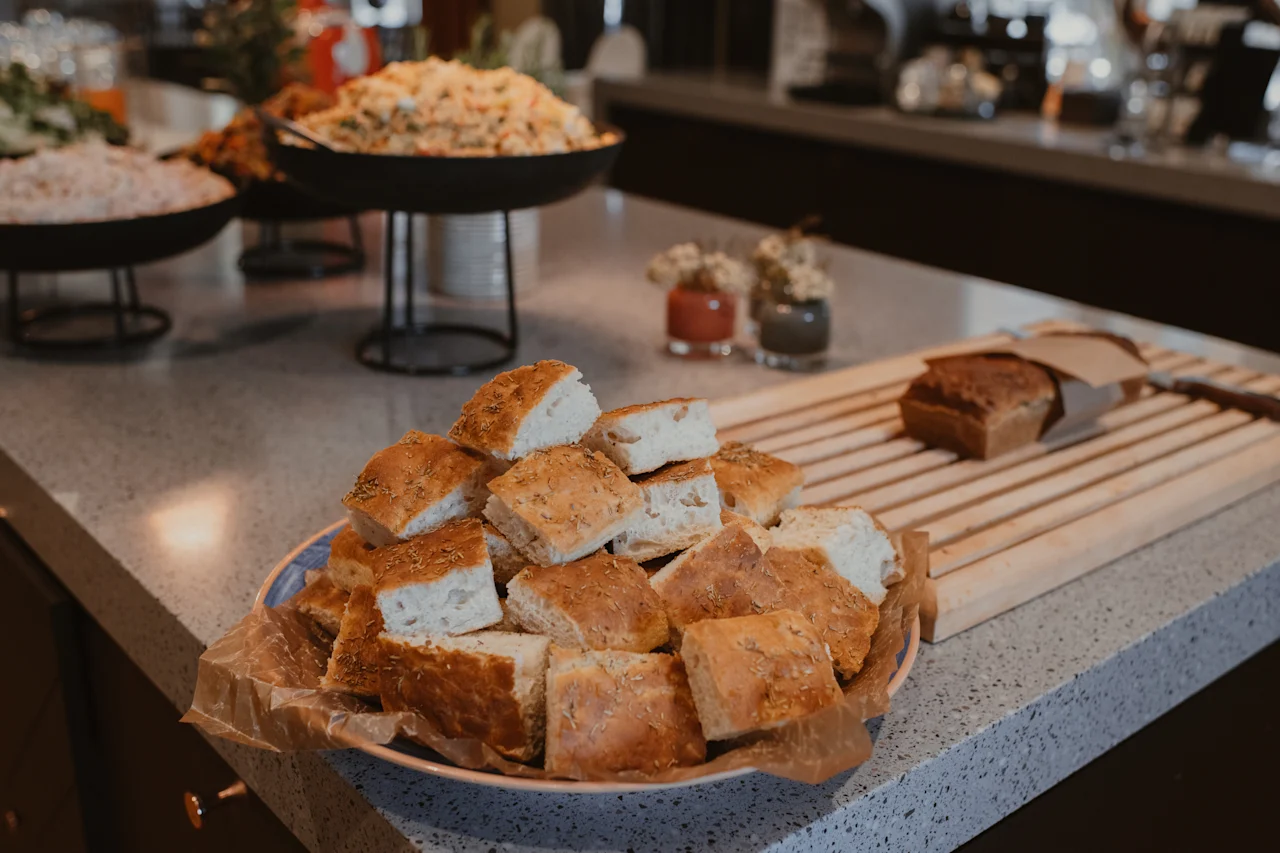 Nærbilde av et buffébord med nybakt brød, med andre deilige retter uskarpe i bakgrunnen.