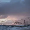 Luminen maisema Svalbardissa vuorineen ja pilvisine taivaineen hämärässä.