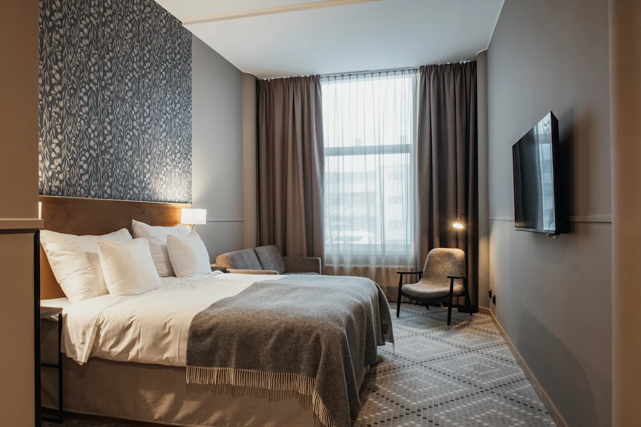 Ett modernt och inbjudande hotellrum med en bekväm säng, en mysig sittgrupp och en väggmonterad TV.