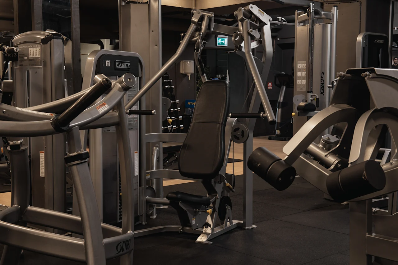 Et moderne fitnesscenter med et udvalg af træningsmaskiner, herunder vægttræningsudstyr, klar til en træningssession.