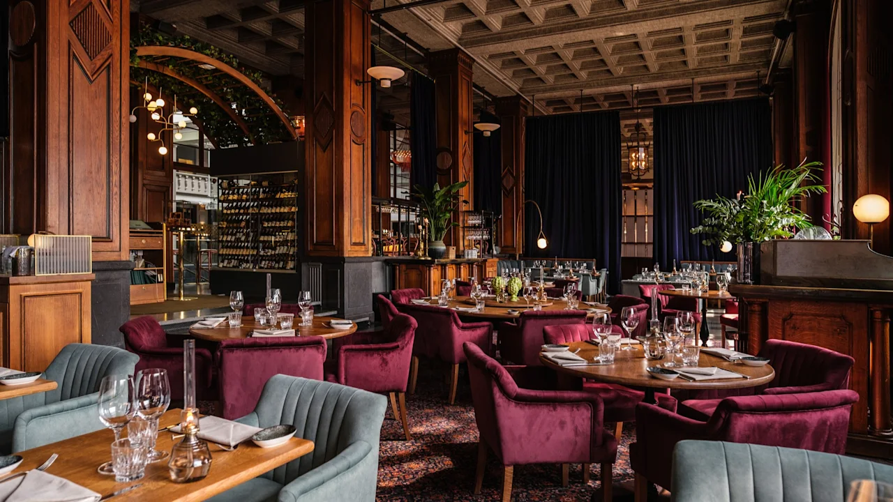 Et elegant restaurantinteriør på Clarion Hotel Post med dekkede bord, plysjseter, varm belysning og rike tredetaljer.