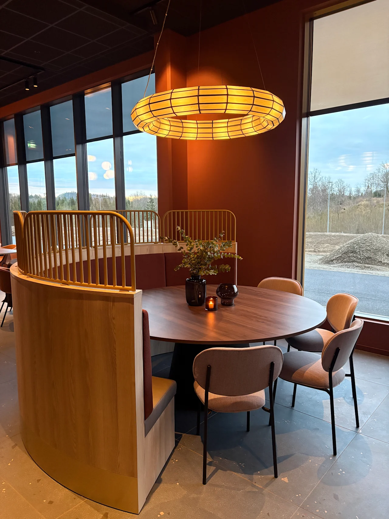 Et koselig, moderne spiseområde med et rundt bord, komfortable sitteplasser og et varmt lys fra en unik sirkulær lysarmatur.