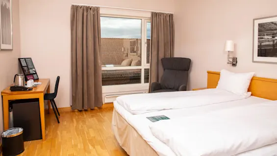 Standard doubleromm at Home Hotel Bryggen, with made bed, window and workspace. 