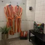 Et koselig velværeområde med to stripete badekåper, tøfler og en plante. En blomstret veske hviler på en benk. Home Hotel Bilan Wellness.