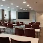 A modern conference room at Home Hotel Uppsala with rows of tables and chairs facing a large screen, ready for a presentation.