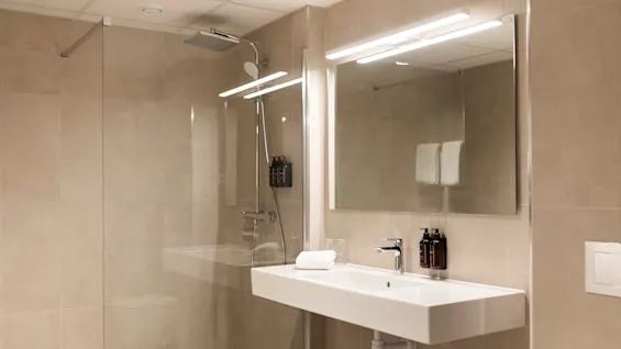 A stylish bathroom with a glass-enclosed shower and a minimalist sink area, perfect for a relaxing start or end to the day.