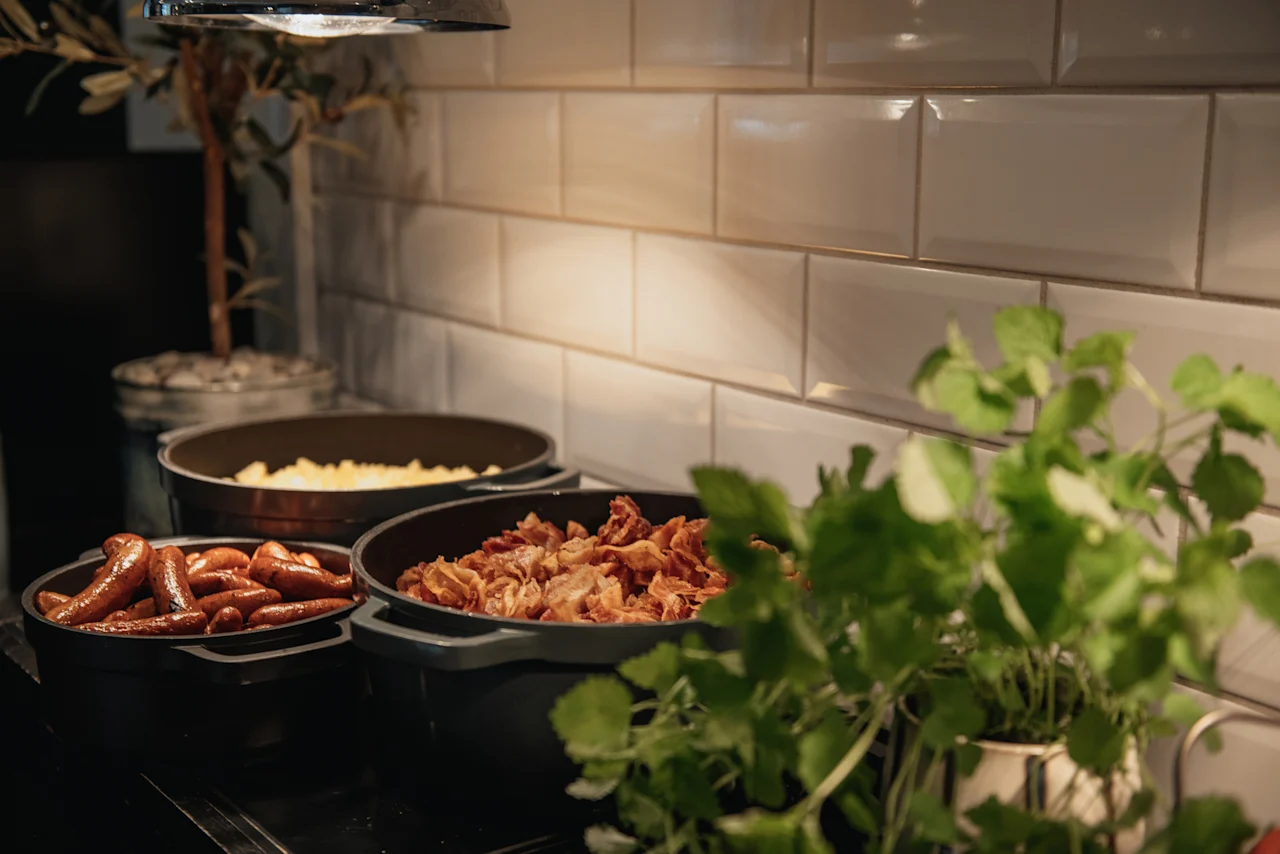 En varm frukostbuffé med korv, bacon och ägg på Home Hotel Grand, Helsingborg, redo för gästerna att njuta av.