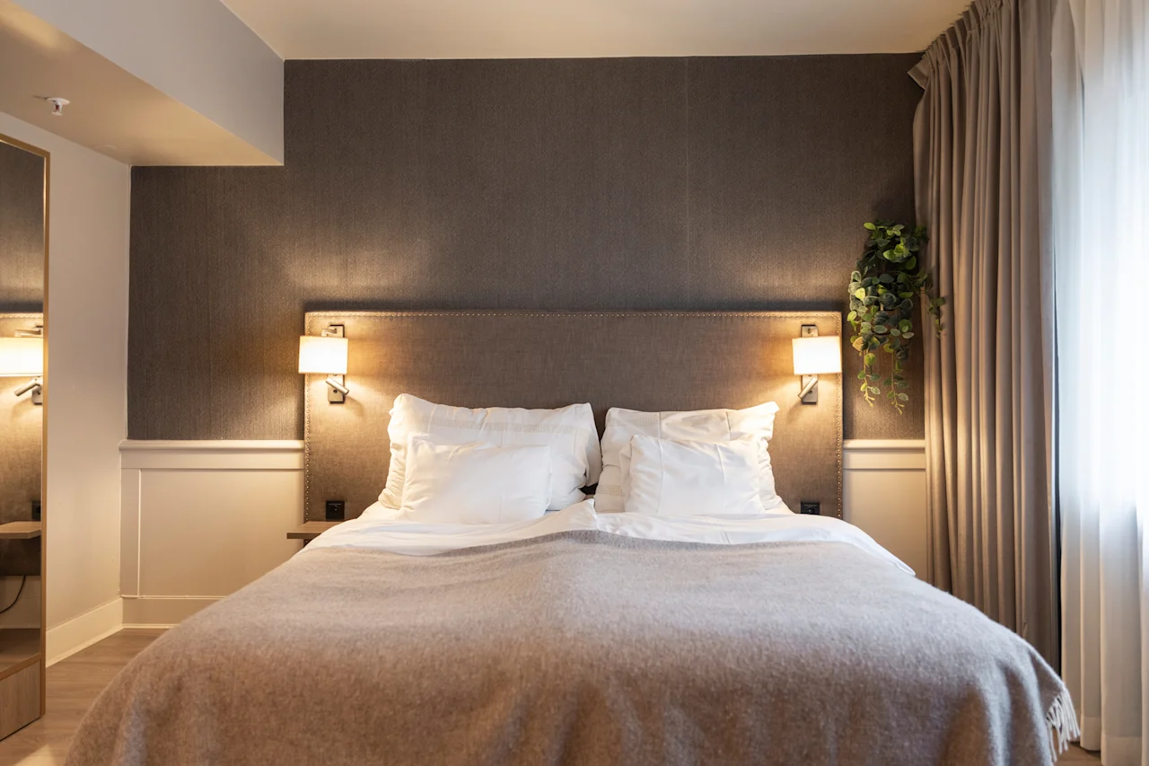A cozy bedroom at Home Hotel Grand Bodø with a large bed, soft pillows, and warm lighting, perfect for relaxation.