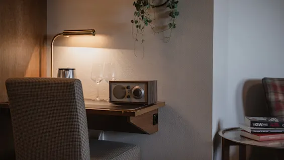 Et hyggeligt skrivebordsområde med en varm lampe, to vinglas og en radio, perfekt til afslapning eller roligt arbejde.
