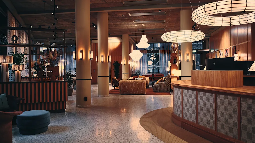 En moderne og innbydende hotellobby med en buet resepsjonsdisk, komfortable sitteplasser og unik takbelysning.