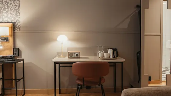 Ett mysigt rum med en väl upplyst skrivbordsplats, med lampa, radio och tefaciliteter, redo för arbete eller avkoppling.