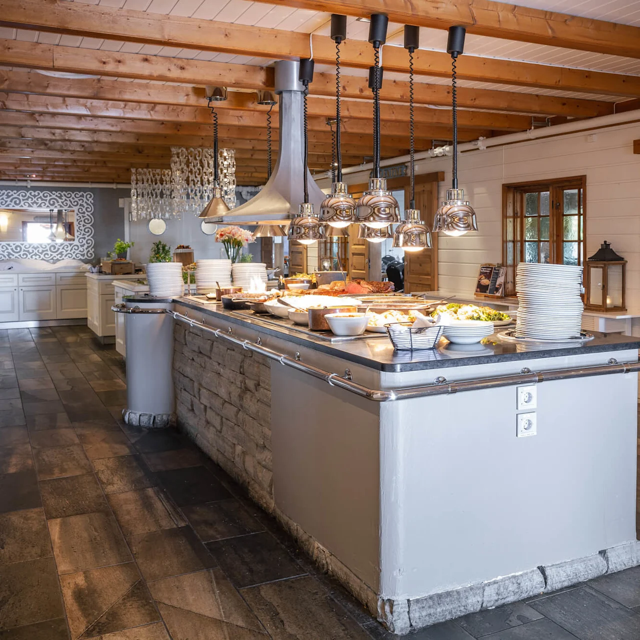 Buffet med tallerkener og mat, inkludert salater og bakverk, på en benkeplate i et spisestue med tredetaljer. Et skilt over står "YGDRASIL".