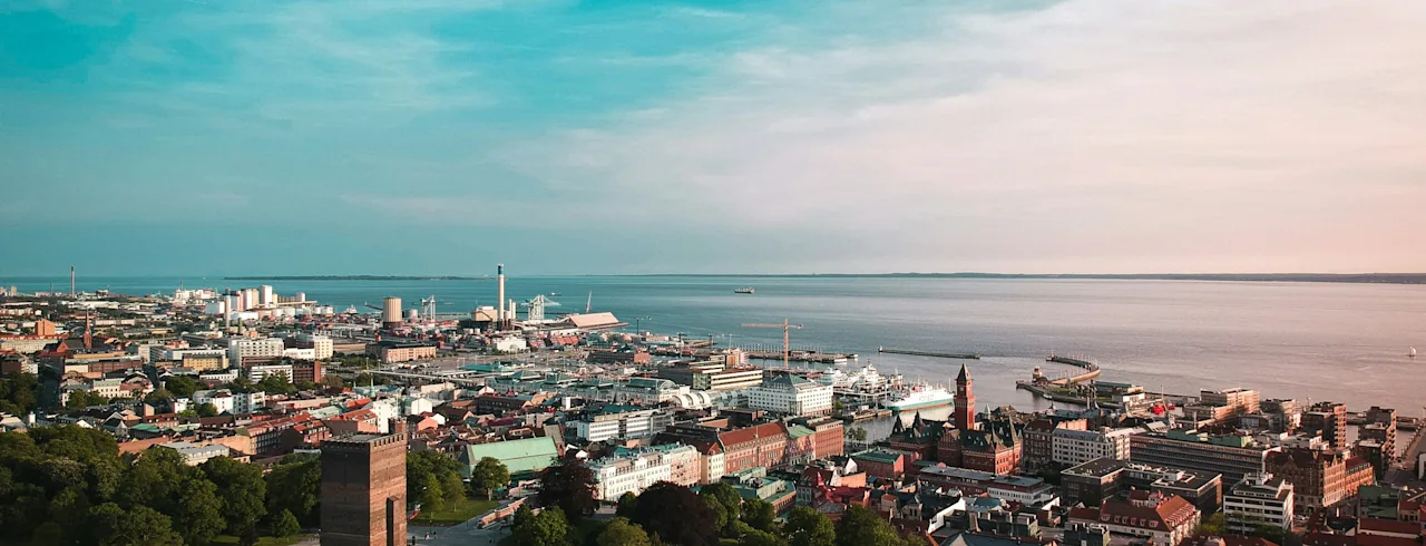 Luftfoto av Helsingborg by og havn under en levende himmel, med historiske bygninger og grøntområder ved vannet.