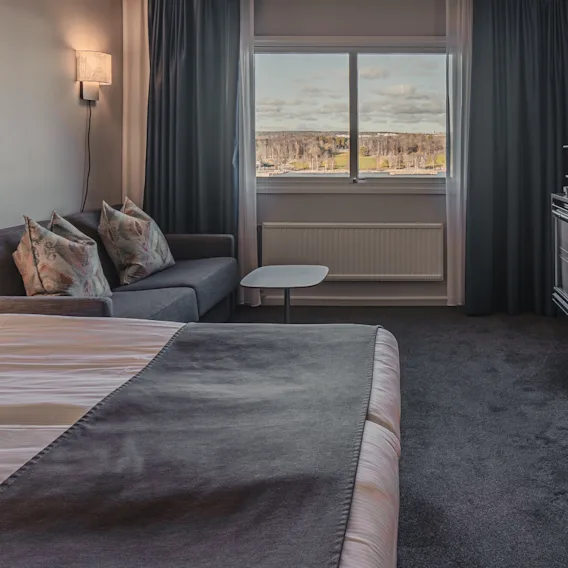 Ett bekvämt hotellrum med en säng, en soffa, ett skrivbord och ett fönster med utsikt över naturen.