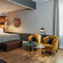 Et stilfullt hotellrom designet for avslapning, med en komfortabel seng og et innbydende sitteområde med to myke lenestoler.