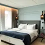 Et moderne og innbydende hotellrom med en komfortabel seng, en koselig lenestol og en flatskjerm-TV.