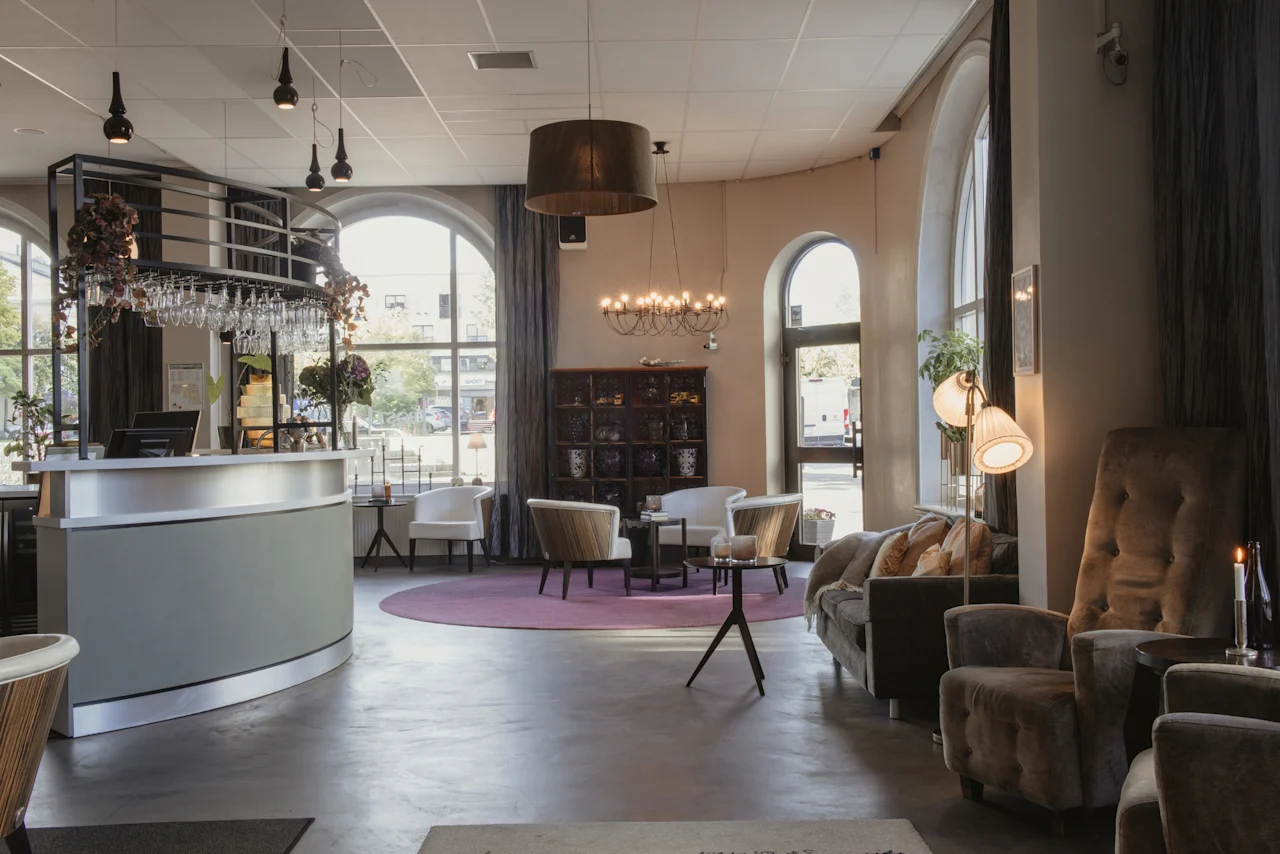 En inbjudande hotellobby med reception och bekväma sittplatser i naturligt ljus från välvda fönster.