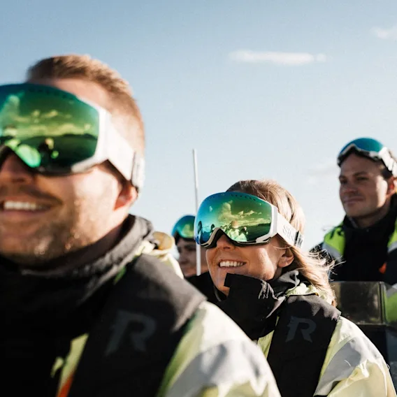 Smilende personer med skibriller og redningsvester på tur med en rask RIB-båt.
