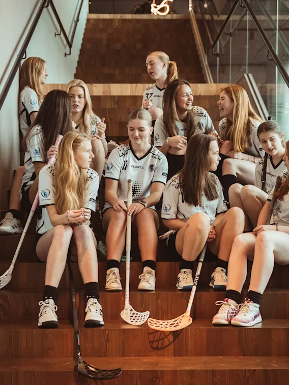 Et innebandylag i uniform slapper av og prater i en moderne tretrapp.