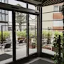 View from inside Home Hotel Uppsala looking out onto a cozy outdoor patio with seating areas and lush green plants.