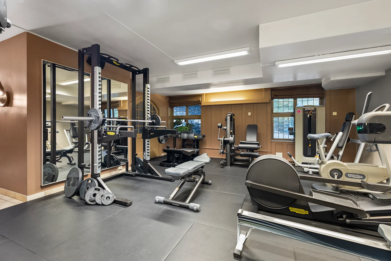 Et velutstyrt hotellgym med ulike treningsapparater, inkludert vekter, benker og kondisjonsutstyr, klart for en treningsøkt.