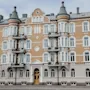 En rikt utsmyckad fyravåningsbyggnad med rundade torn och flera fönster visar en klassisk arkitektur. Balkonger på varje våning är försedda med räcken, i en stadsmiljö.