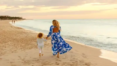 Child and mother holding hands and walking on beach