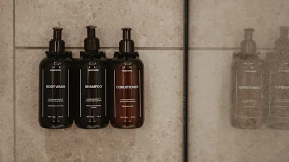 Home Hotel Tapetfabriken shower with BODY WASH, SHAMPOO, and CONDITIONER bottles, reflected in the glass.