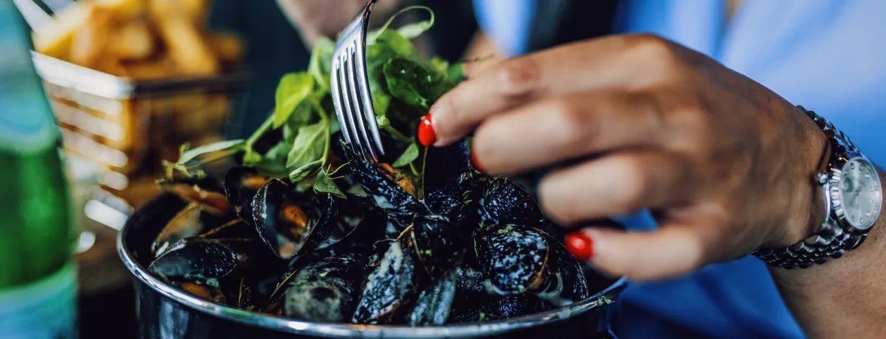 Kvinna äter musslor och pommes frites på restaurang The Social Bar & Bistro.