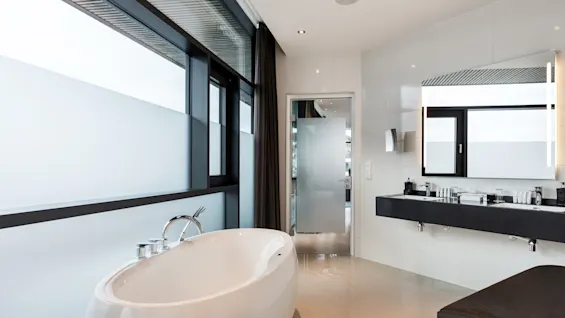 Et luksuriøst bad på Quality Hotel Ulstein med et frittstående badekar ved et stort vindu og en elegant dobbeltservant.
