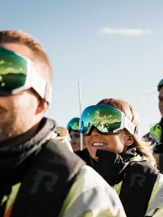 Smilende personer med skibriller og redningsvester på tur med en rask RIB-båt.