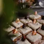 A delightful spread of small cakes with white frosting, fresh berries, and herbs on a wooden board at Home Hotel Uppsala. AMERIKAN.