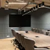 An empty, modern conference room with a large screen, a long wooden table, and many chairs, set for collaboration.