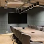 An empty, modern conference room with a large screen, a long wooden table, and many chairs, set for collaboration.