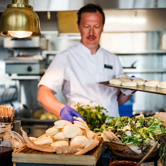 Kokk tilbereder fersk mat og boller på et kjøkken ved Quality Hotel Grand Larvik. Synlig tekst: GRAND BISTRO.