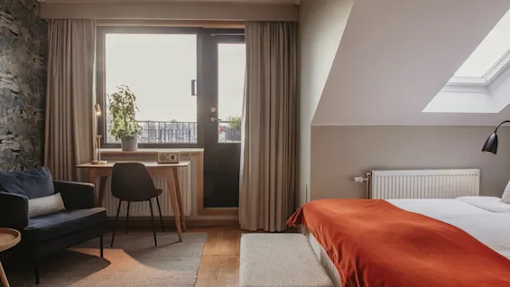 Et lyst og indbydende hotelværelse på Home Hotel Wellington med seng, skrivebord ved altan og ovenlysvindue.